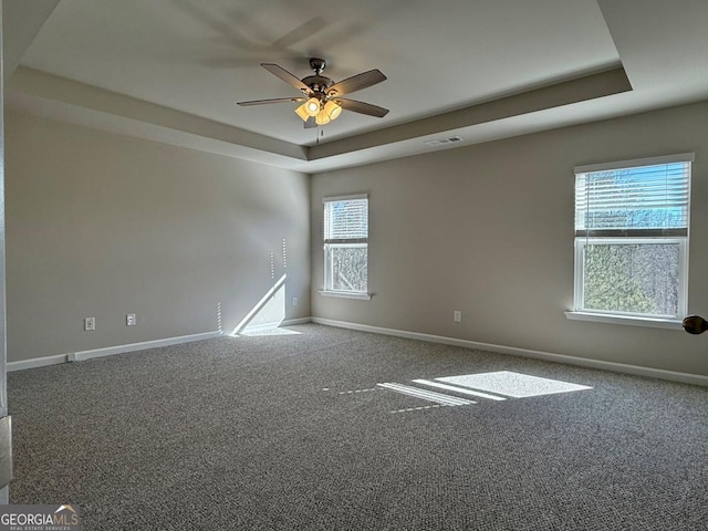 carpeted empty room featuring a tray ceiling and ceiling fan