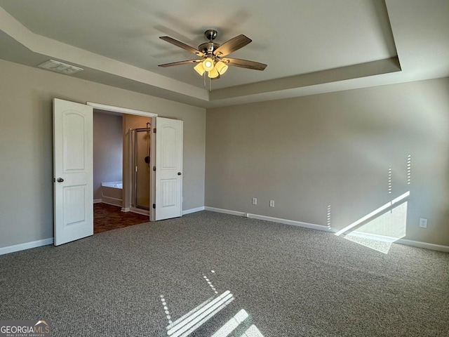 unfurnished bedroom with a tray ceiling, ceiling fan, and dark colored carpet