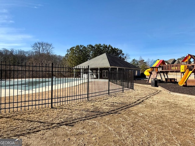 view of playground featuring a view of the beach, a water view, and a covered pool