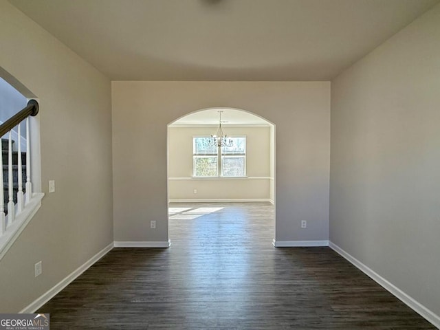 unfurnished room featuring dark hardwood / wood-style flooring and an inviting chandelier