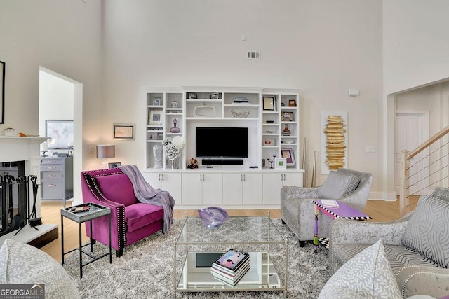 living room with light hardwood / wood-style floors and a high ceiling