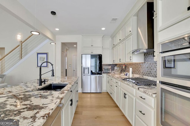 kitchen featuring appliances with stainless steel finishes, light stone counters, sink, pendant lighting, and white cabinets