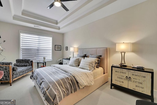 carpeted bedroom with a raised ceiling, ceiling fan, and ornamental molding