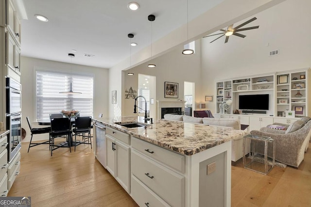 kitchen with white cabinets, sink, an island with sink, and pendant lighting