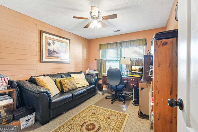 office with ceiling fan, light carpet, a textured ceiling, and wood walls