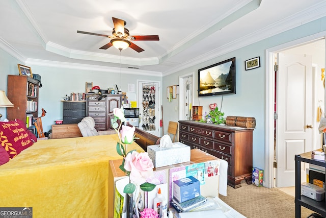 bedroom featuring ceiling fan, ornamental molding, a tray ceiling, and carpet flooring