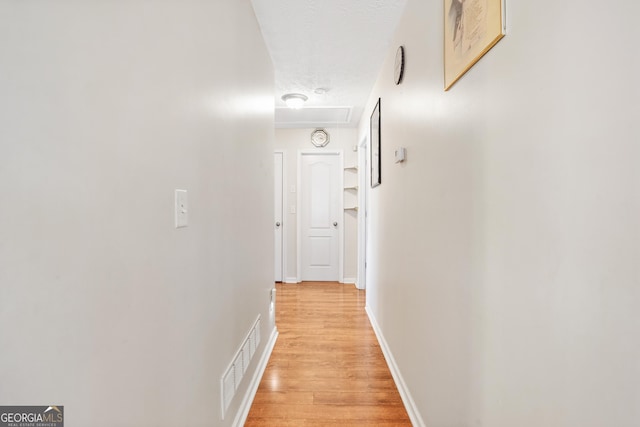 hallway featuring a textured ceiling and light wood-type flooring