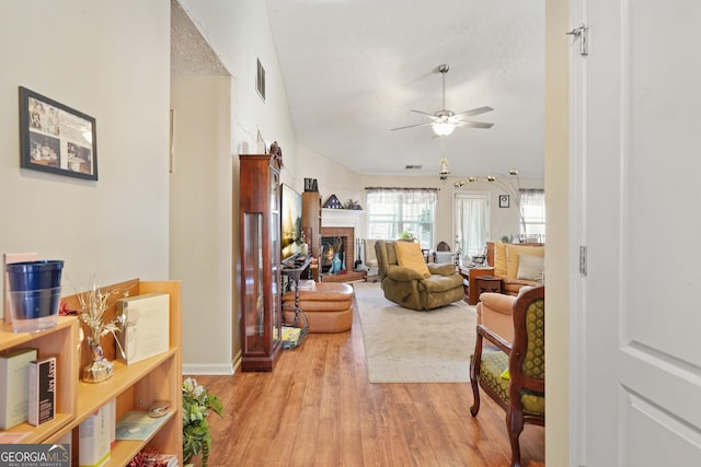 living room featuring a brick fireplace, ceiling fan, and light hardwood / wood-style flooring