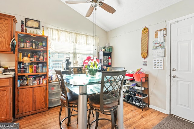 dining space featuring vaulted ceiling, ceiling fan, and light wood-type flooring