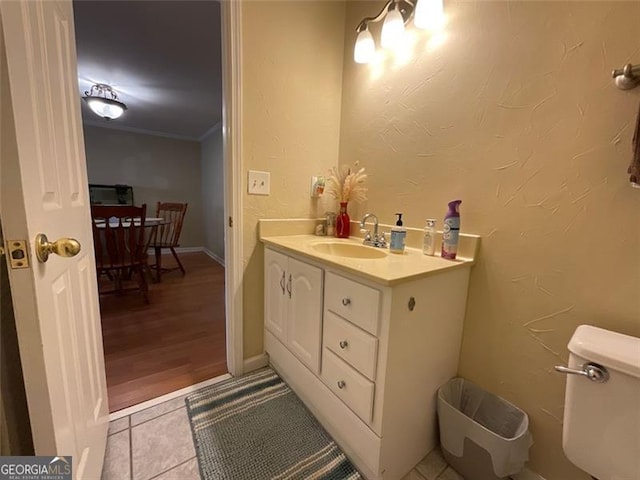 bathroom featuring tile patterned flooring, vanity, toilet, and crown molding