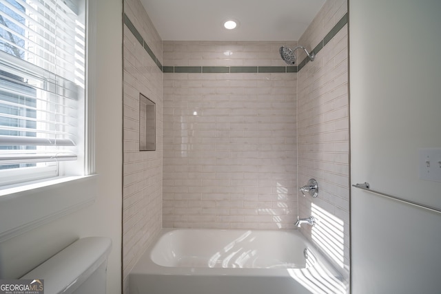 bathroom featuring tiled shower / bath and toilet