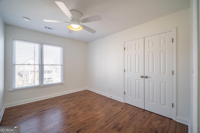 unfurnished bedroom featuring dark hardwood / wood-style floors, ceiling fan, and a closet