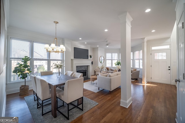 dining area featuring ornate columns, ornamental molding, dark wood-type flooring, and ceiling fan with notable chandelier