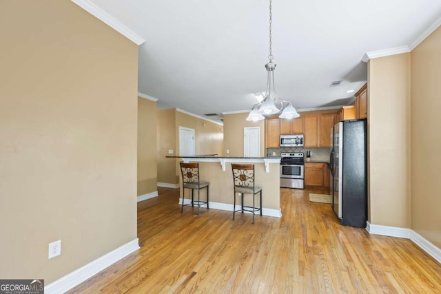 kitchen featuring stainless steel appliances, a kitchen breakfast bar, crown molding, pendant lighting, and decorative backsplash