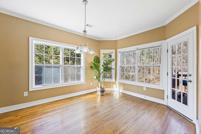 unfurnished dining area featuring crown molding, hardwood / wood-style floors, and a notable chandelier