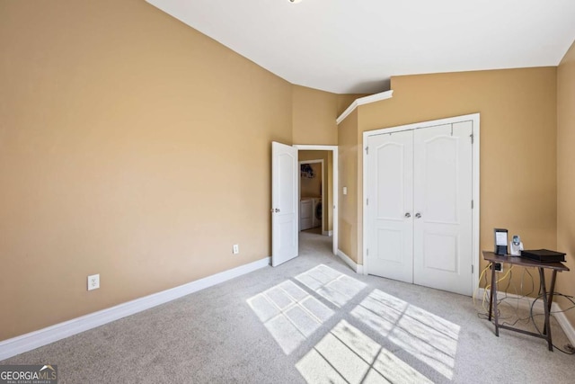 bedroom with light colored carpet, lofted ceiling, and a closet