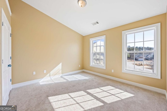 spare room with light colored carpet and vaulted ceiling