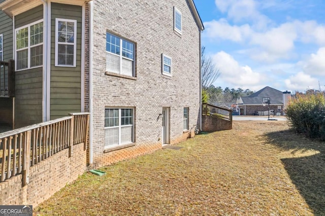 view of property exterior featuring a wooden deck and a lawn