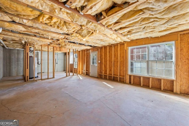 miscellaneous room with concrete floors, a healthy amount of sunlight, and water heater