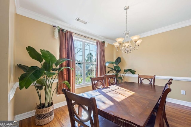 dining space with hardwood / wood-style flooring, plenty of natural light, an inviting chandelier, and ornamental molding