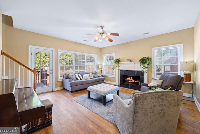 living room with ceiling fan, a fireplace, and wood-type flooring