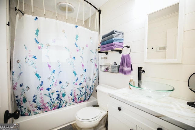 full bathroom with wood walls, shower / bath combo with shower curtain, vanity, and toilet