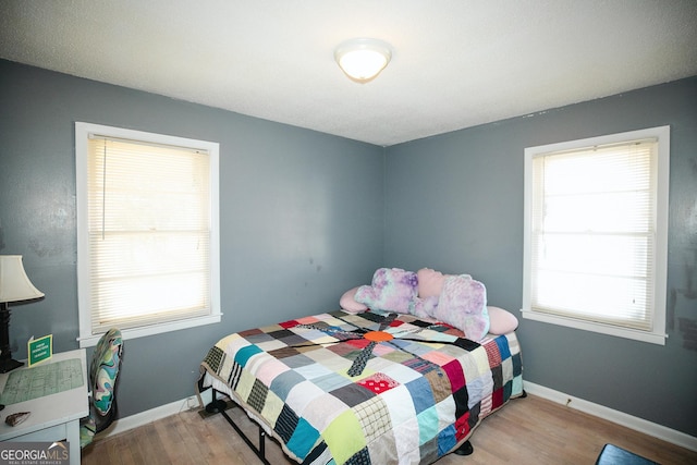 bedroom with multiple windows and wood-type flooring