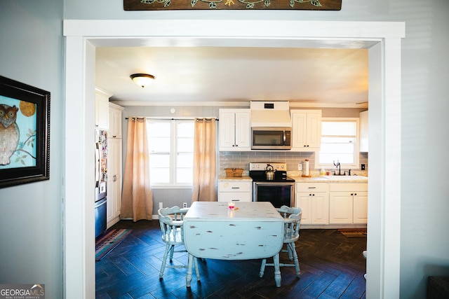 kitchen featuring stainless steel appliances, white cabinets, dark parquet floors, and decorative backsplash