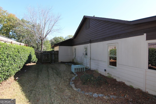 view of side of property featuring central AC and a lawn