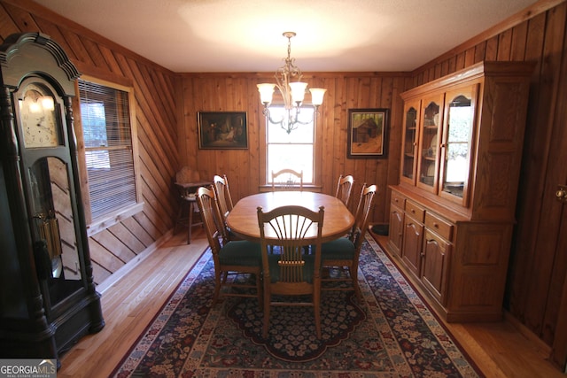 dining space with hardwood / wood-style flooring, an inviting chandelier, and wood walls