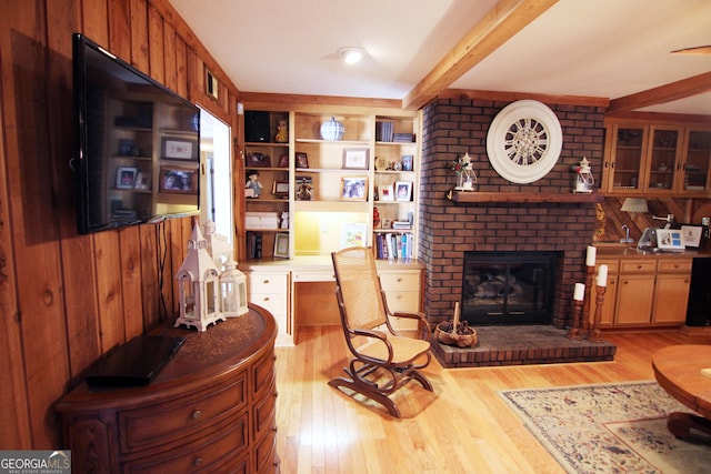 living room with beamed ceiling, a fireplace, wooden walls, and light hardwood / wood-style flooring