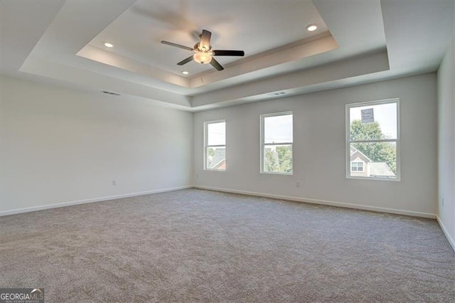 carpeted spare room featuring ceiling fan and a tray ceiling