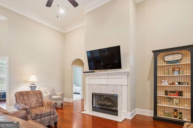 living room with ceiling fan, a fireplace, ornamental molding, and hardwood / wood-style flooring