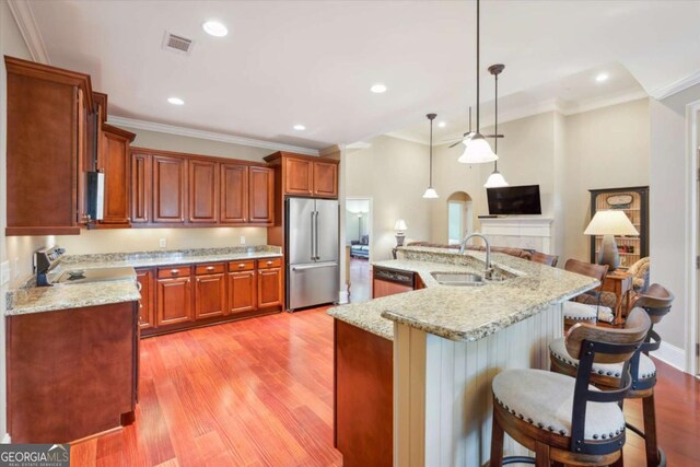 kitchen featuring pendant lighting, a kitchen breakfast bar, sink, an island with sink, and stainless steel appliances