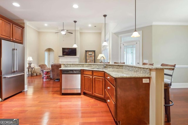 kitchen featuring decorative light fixtures, sink, stainless steel appliances, and a breakfast bar area