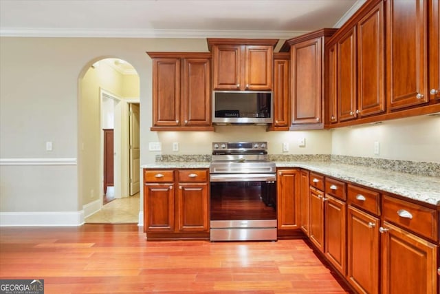 kitchen with light hardwood / wood-style floors, light stone countertops, stainless steel appliances, and ornamental molding