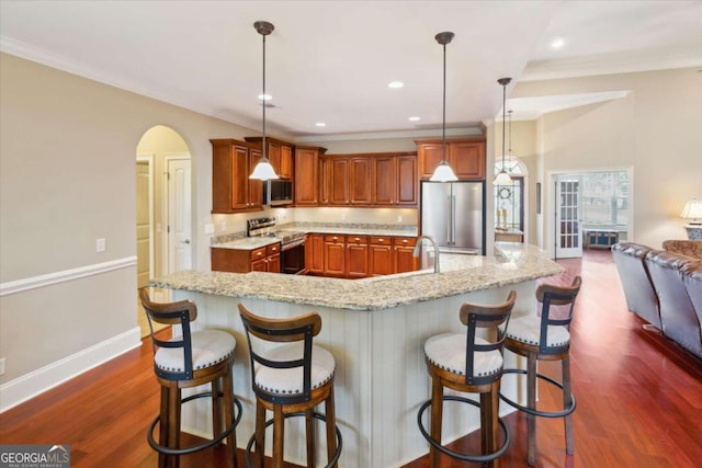 kitchen with a kitchen bar, appliances with stainless steel finishes, a spacious island, dark wood-type flooring, and pendant lighting