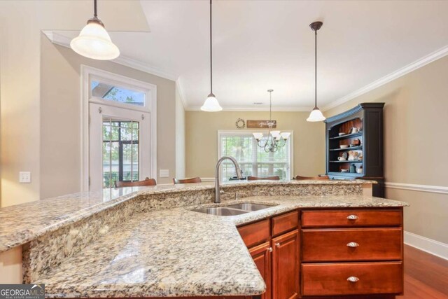 kitchen with sink, light stone countertops, ornamental molding, decorative light fixtures, and dark hardwood / wood-style flooring