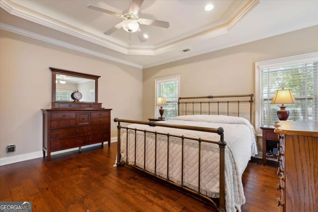 bedroom with ornamental molding, a tray ceiling, ceiling fan, dark wood-type flooring, and multiple windows