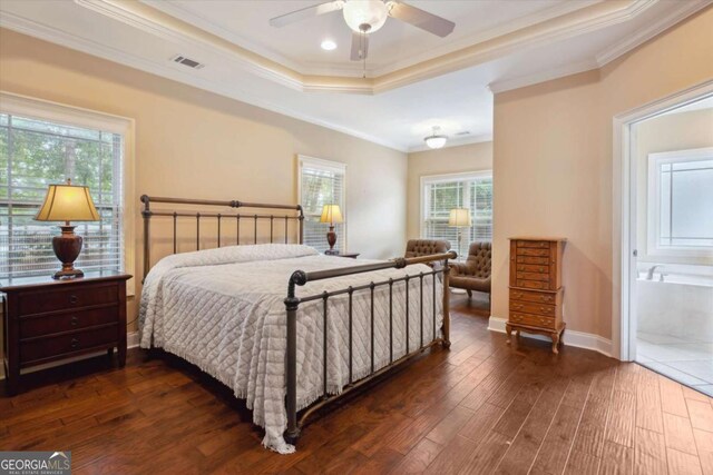 bedroom featuring dark hardwood / wood-style flooring, ensuite bath, a raised ceiling, ceiling fan, and crown molding