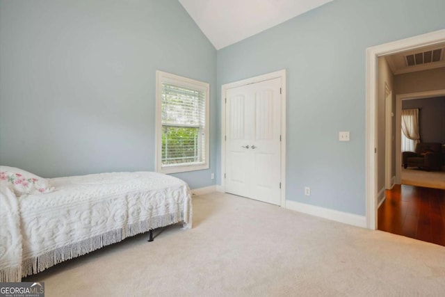 carpeted bedroom featuring lofted ceiling and a closet