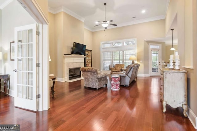 living room with ceiling fan, dark hardwood / wood-style flooring, ornamental molding, and a fireplace