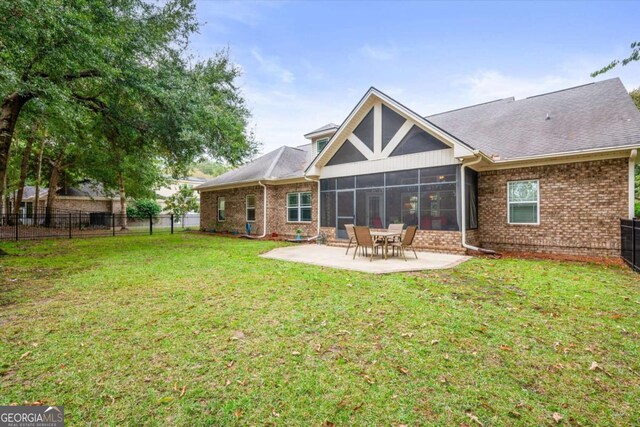 back of property with a sunroom, a patio area, and a yard