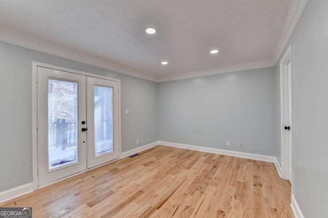 empty room featuring french doors, light hardwood / wood-style flooring, and crown molding