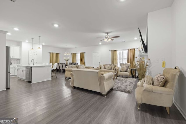 living room with sink, dark wood-type flooring, and ceiling fan with notable chandelier