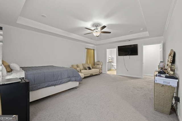 carpeted bedroom featuring a tray ceiling, ceiling fan, crown molding, and ensuite bathroom