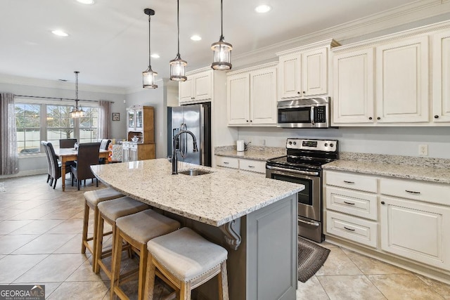 kitchen featuring light stone counters, hanging light fixtures, appliances with stainless steel finishes, and a center island with sink