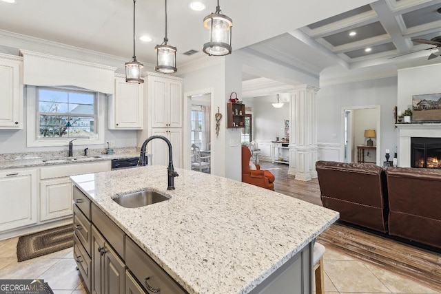 kitchen featuring decorative light fixtures, sink, a center island with sink, and coffered ceiling