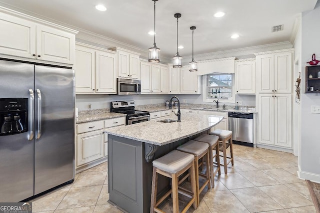 kitchen featuring sink, appliances with stainless steel finishes, an island with sink, white cabinets, and light stone counters