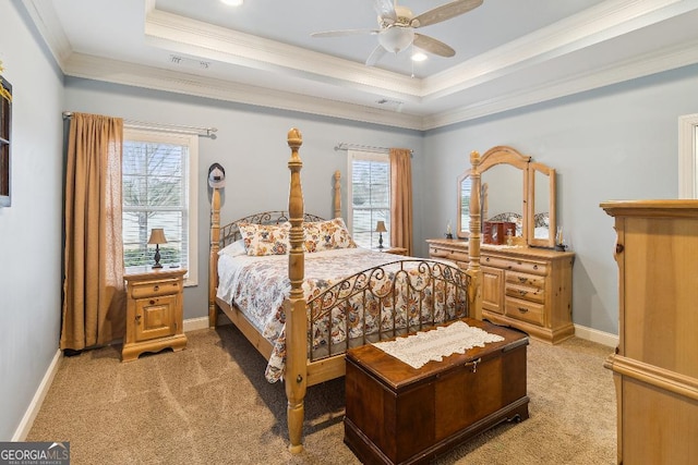 bedroom featuring ceiling fan, a tray ceiling, ornamental molding, and light carpet